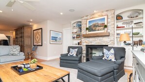 Un salon avec une cheminée, deux fauteuils, un canapé et une table basse.