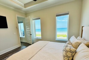 A bedroom with a bed, a door, and a view of the ocean. - Beautiful Oceanfront House with Pool in Flagler Beach (Flagler Beach)