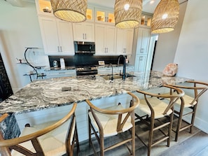 A kitchen with a large island, white cabinets, a microwave, and a stove. - Beautiful Oceanfront House with Pool in Flagler Beach (Flagler Beach)