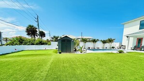 A well-maintained backyard with a swimming pool, a small shed, and a white fence. - Beautiful Oceanfront House with Pool in Flagler Beach (Flagler Beach)