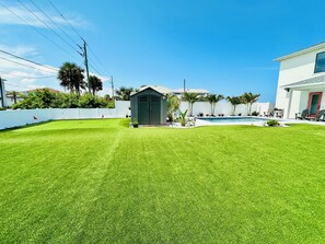 A well-maintained backyard with a swimming pool, a small shed, and a white fence. - Beautiful Oceanfront House with Pool in Flagler Beach (Flagler Beach)