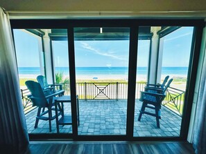 Une chambre avec vue sur la plage, accessible par de grandes portes vitrées.