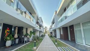 A modern hotel corridor with glass balconies, potted plants, and a clear sky. - Charming 3-bedroom condo with AC right by the beach in cozy Coveñas (Coveñas)