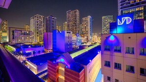 A nighttime cityscape with illuminated buildings and a prominent hotel sign. - Brickell Area| Free Parking| Balcony| Rooftop Pool (Miami)