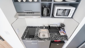 A compact kitchen with a sink, microwave, kettle, and a coffee machine. - Hache Palermo by IPPA (Buenos Aires)