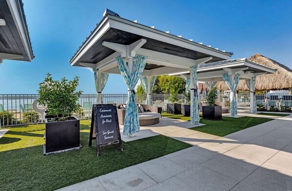 A covered outdoor seating area with a sign indicating availability for rent and guest services.