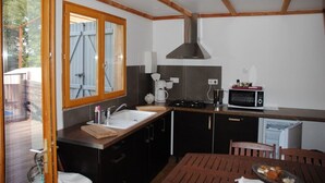 Eine kompakte Küche mit Spüle, Herd, Mikrowelle und einem Fenster mit Blick ins Freie.