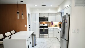 A modern kitchen with white cabinets, a stainless steel refrigerator, a microwave, and a stove. - Hollywood 1811 (Hollywood)