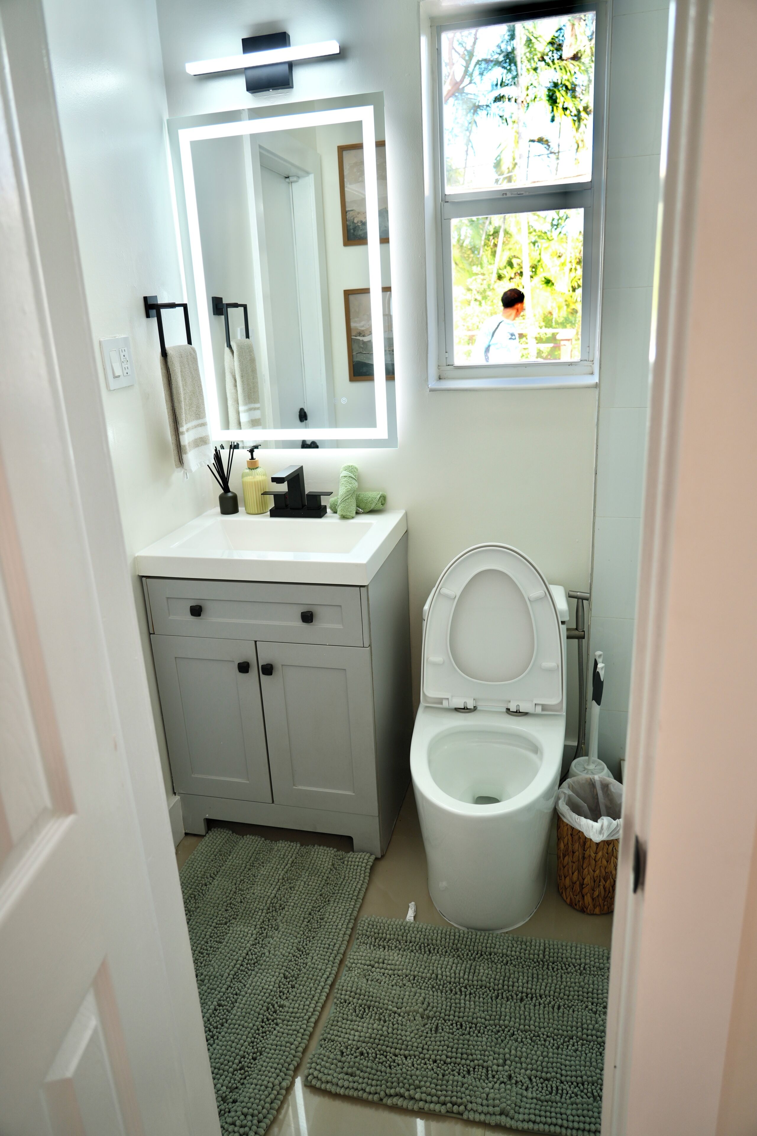 Un baño con inodoro, lavabo, espejo y ventana.