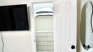 A bathroom with a white door, a mounted TV, a mirror, and a tiled floor. - Hollywood 1811 (Hollywood)