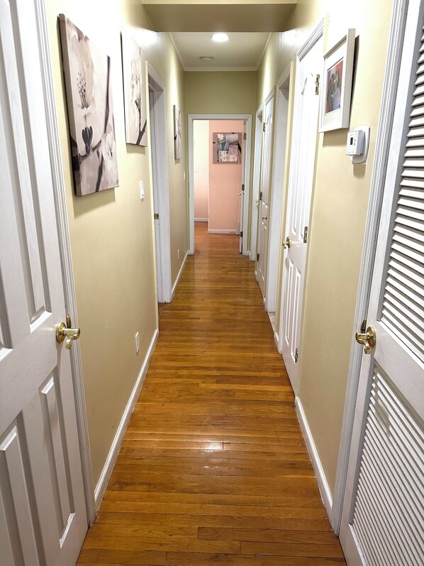 A hallway with wooden flooring, white doors, and wall-mounted pictures.
