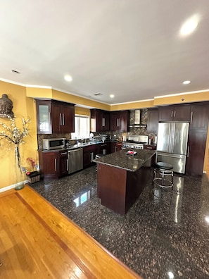 A modern kitchen with dark wood cabinets, stainless steel appliances, and a granite island.