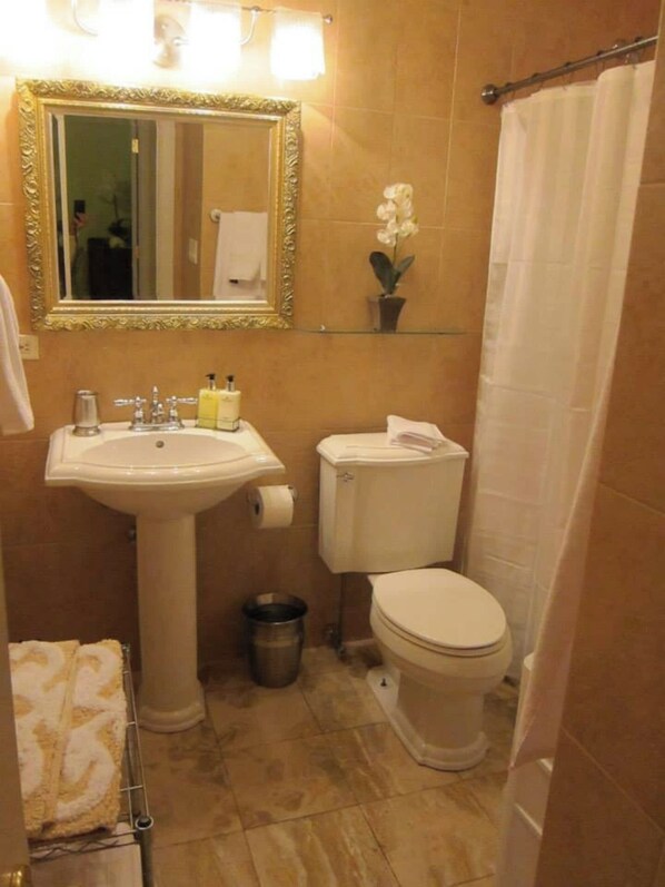 Un baño con lavamanos pedestal, inodoro y cortina de ducha.
