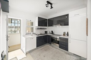Une cuisine moderne avec des meubles de rangement blancs et noirs, un four encastré et une fenêtre donnant sur la ville.