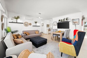 Una sala moderna con un sofá, un reposapiés y un sillón colorido.
