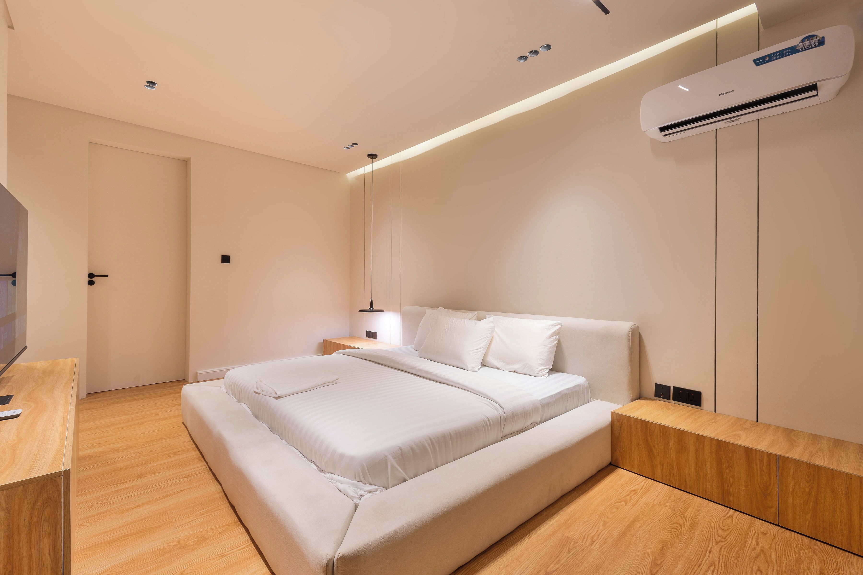 A modern bedroom with a bed, bedside table, and an air conditioning unit.