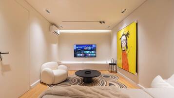 A modern living room with a flat-screen TV, a sofa, a coffee table, and a painting on the wall.