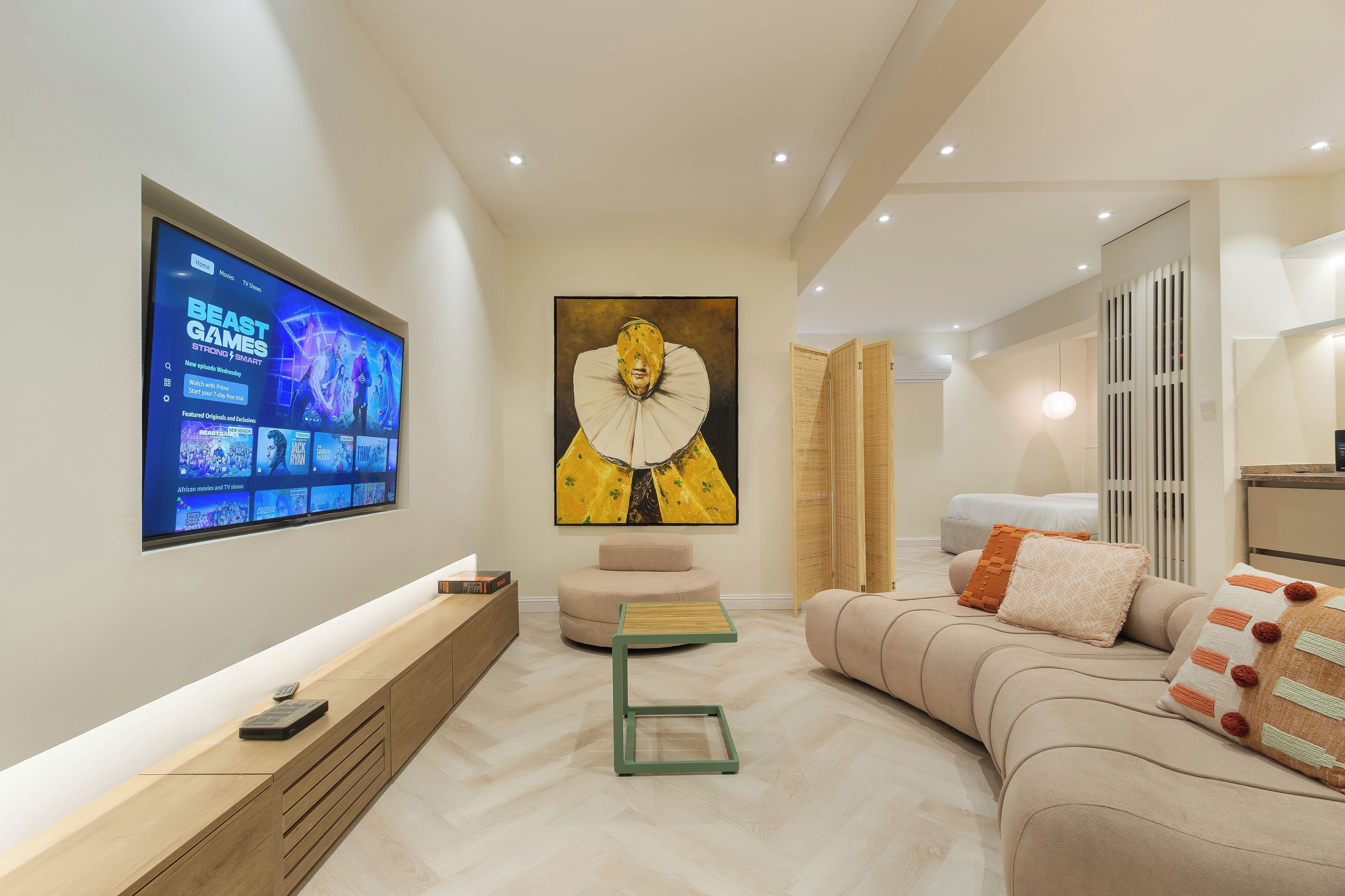 Una sala moderna con una televisión de pantalla plana, un cuadro abstracto grande, un sofá y una mesa de centro de madera.