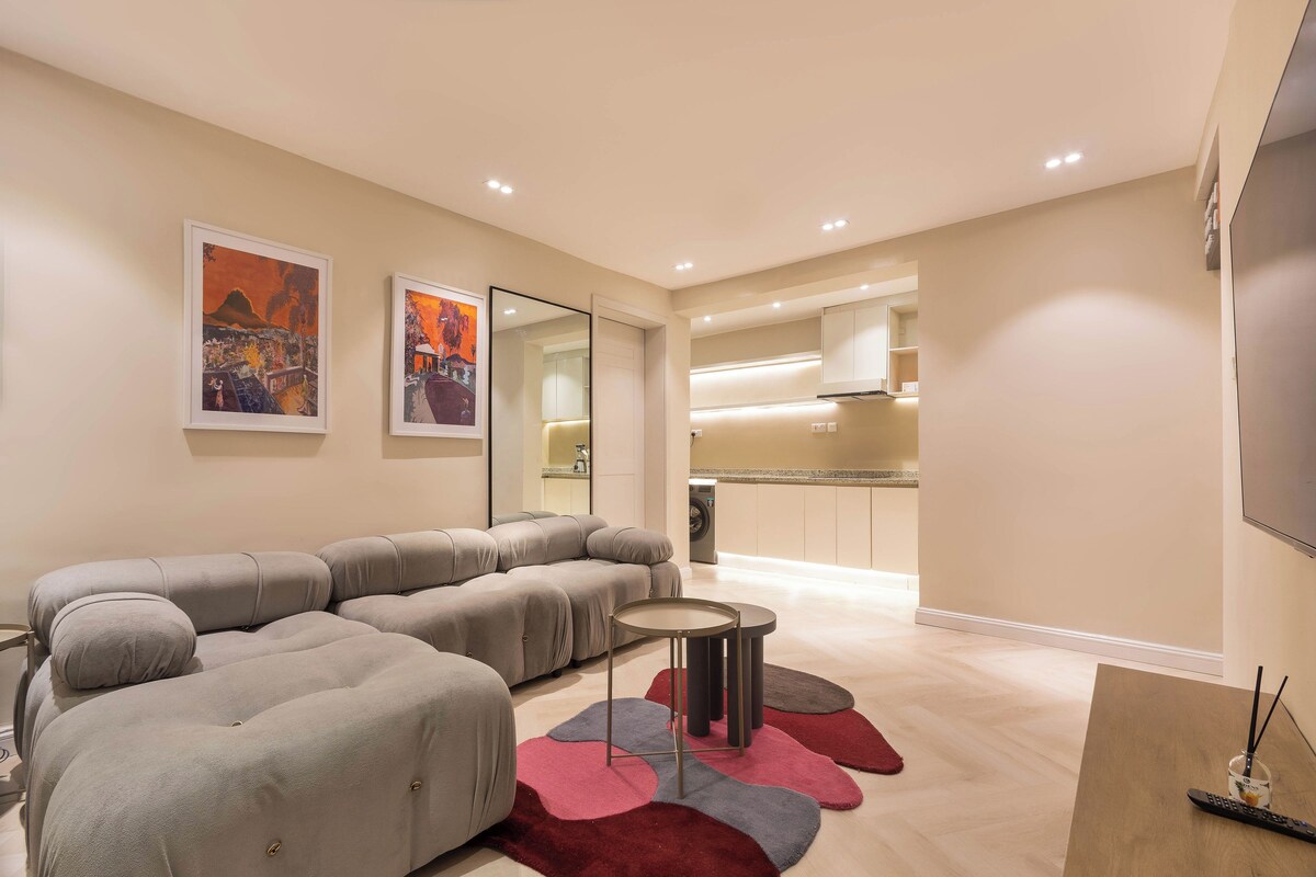 A modern living room with a sectional sofa, a small round table, and a red and grey rug.