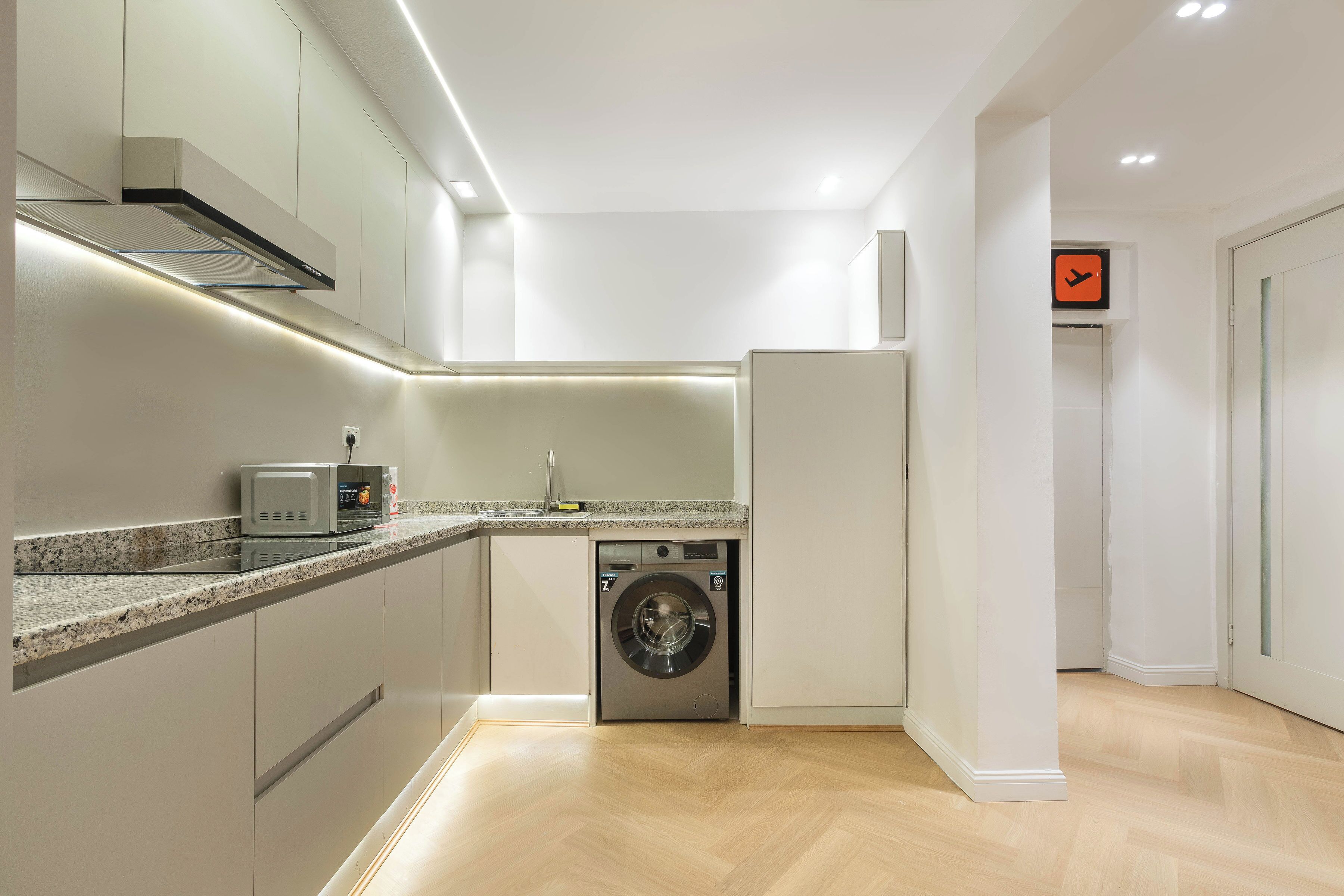 A compact kitchen with a built-in washing machine, a microwave, and a refrigerator.
