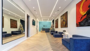 A modern interior with a herringbone floor, blue seating, a large mirror, and artwork on the walls. - The District Lekki (Lekki)