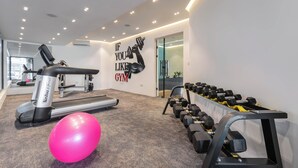 Ett gym med löpband, hantlar och en rosa träningsboll.