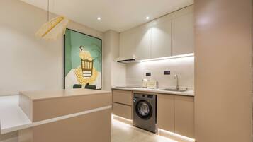 Una cucina moderna con lavatrice integrata, una lampada a sospensione e un quadro di grandi dimensioni appeso al muro.