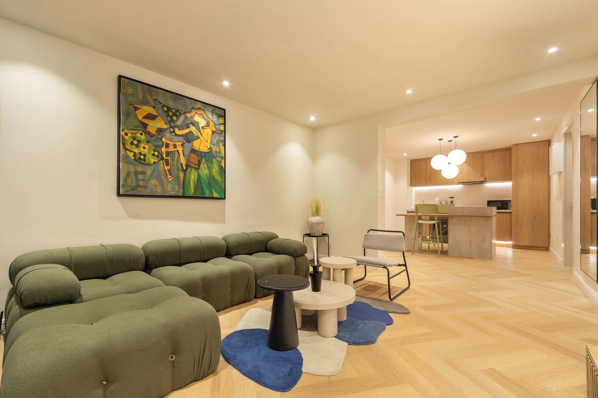 A modern living room with a sectional sofa, a round coffee table, and a painting on the wall.