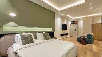 Quarto de hotel moderno com uma cama grande, televisão, escrivaninha e área de estar.