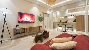 A modern living room with a flat-screen TV, a sofa, a coffee table, and a dining area with chairs and a small table. - The District Lekki (Lekki)