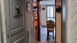 A hallway with a wooden door, a radiator, a chair, and a sign on the wall. - 6-PERSON APARTMENT PRALOGNAN LA VANOISE (Pralognan-la-Vanoise)