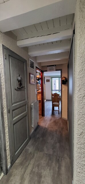 Ein Flur mit einer Holztür, einem Heizkörper, einem Stuhl und einem Schild an der Wand.
