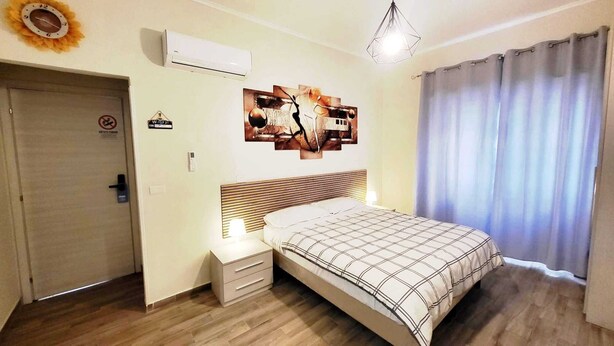A bedroom with a bed, nightstand, wall art, air conditioning unit, and a door. - HuB ROME Tourist Accommodation (Roma)