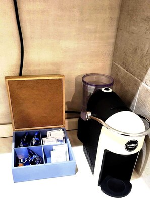 Eine Kaffeemaschine und eine Flasche Wasser in einer Box auf einer Arbeitsplatte.