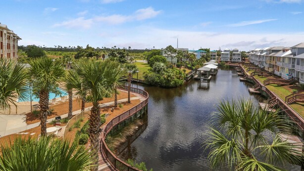 A riverside hotel with a waterway, palm trees, and a bridge. - Waterside Village Cottage 3222 - Sandy Crab (Port St. Joe)