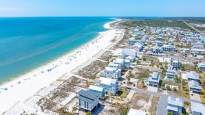 An aerial view of a coastal area with a beach, houses, and a road. - Waterside Village Cottage 3222 - Sandy Crab (Port St. Joe)