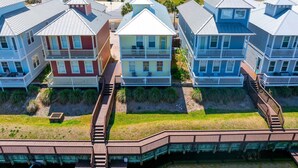 A coastal residential area with multi-story houses, a wooden boardwalk, and a beach in the background. - Waterside Village Cottage 3222 - Sandy Crab (Port St. Joe)