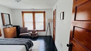Une chambre à coucher comprenant un lit, une commode, une chaise et une fenêtre donnant sur un beau paysage.