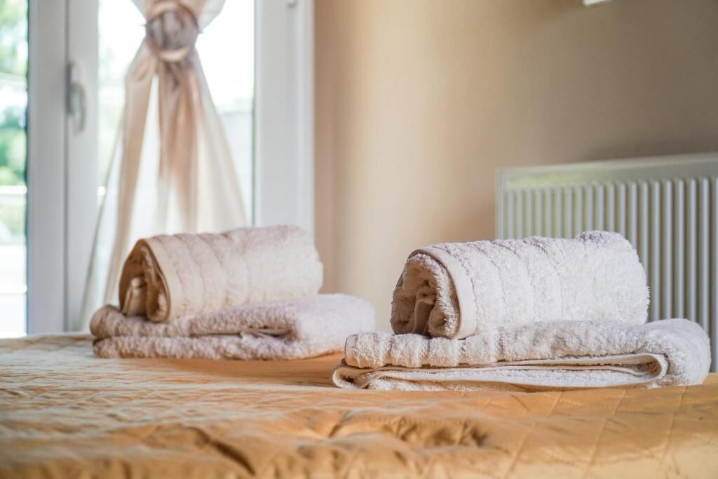 Un letto con due asciugamani arrotolati e una finestra con tende.