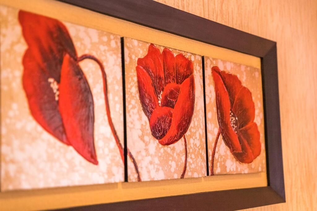 A framed artwork with three red poppy flowers.