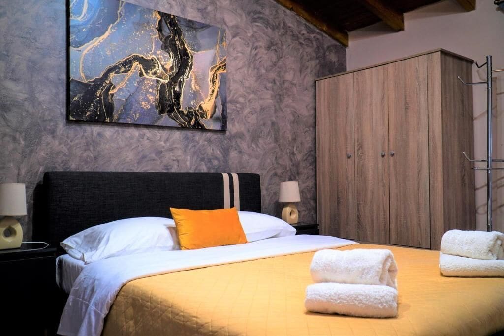 Une chambre d’hôtel avec un lit, une armoire en bois, un mur en marbre et un tableau.