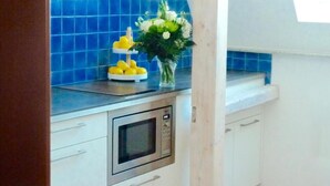 A kitchen with blue tiles, a microwave, and a vase with flowers. - Hotel Zum Bügeleisen (Duisburg)
