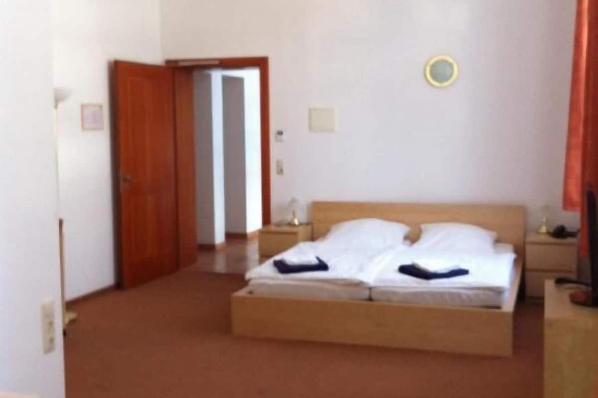 A hotel room with a bed, a nightstand, a chair, and a door.