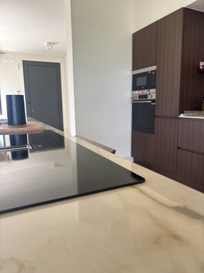 Una cucina con un piano di lavoro nero, un forno a microonde e mobili impiallacciati in legno.