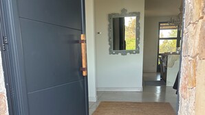 En gang med en mørk dør, et spejl, en måtte og en stenvæg.