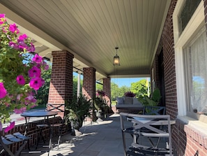 A covered patio area with brick pillars, outdoor seating, and potted plants. - The Painted Petal: A Historic 5 Bedroom Mini Estate Perfect for Groups (Breinigsville)