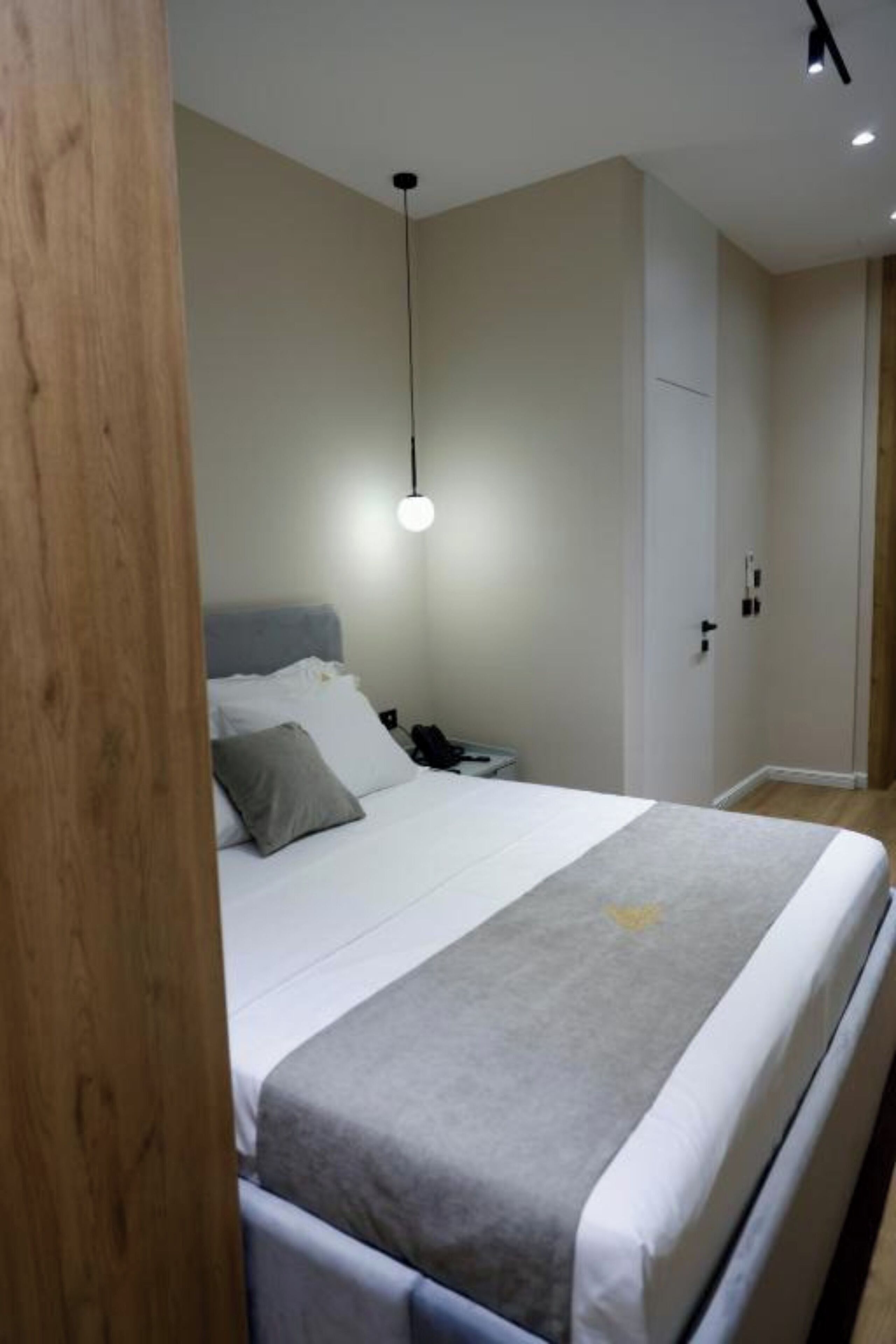 Una camera da letto con un letto, un comodino e una lampada a sospensione.