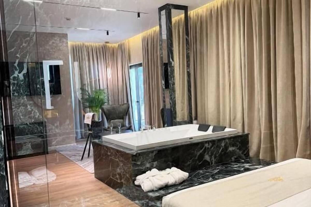Un baño moderno con piso de mármol, una bañera amplia y dos camas.