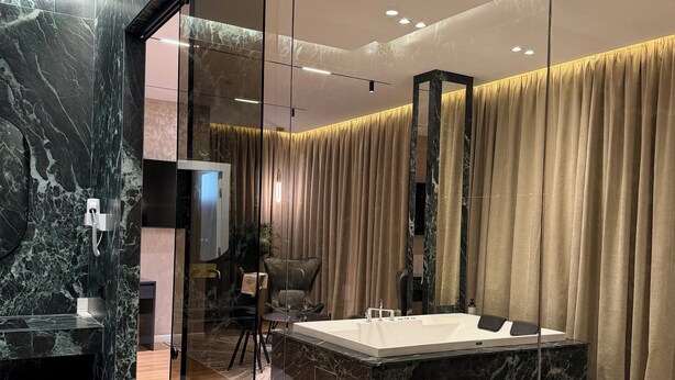 A modern bathroom with a marble sink, a bathtub, and a shower area.