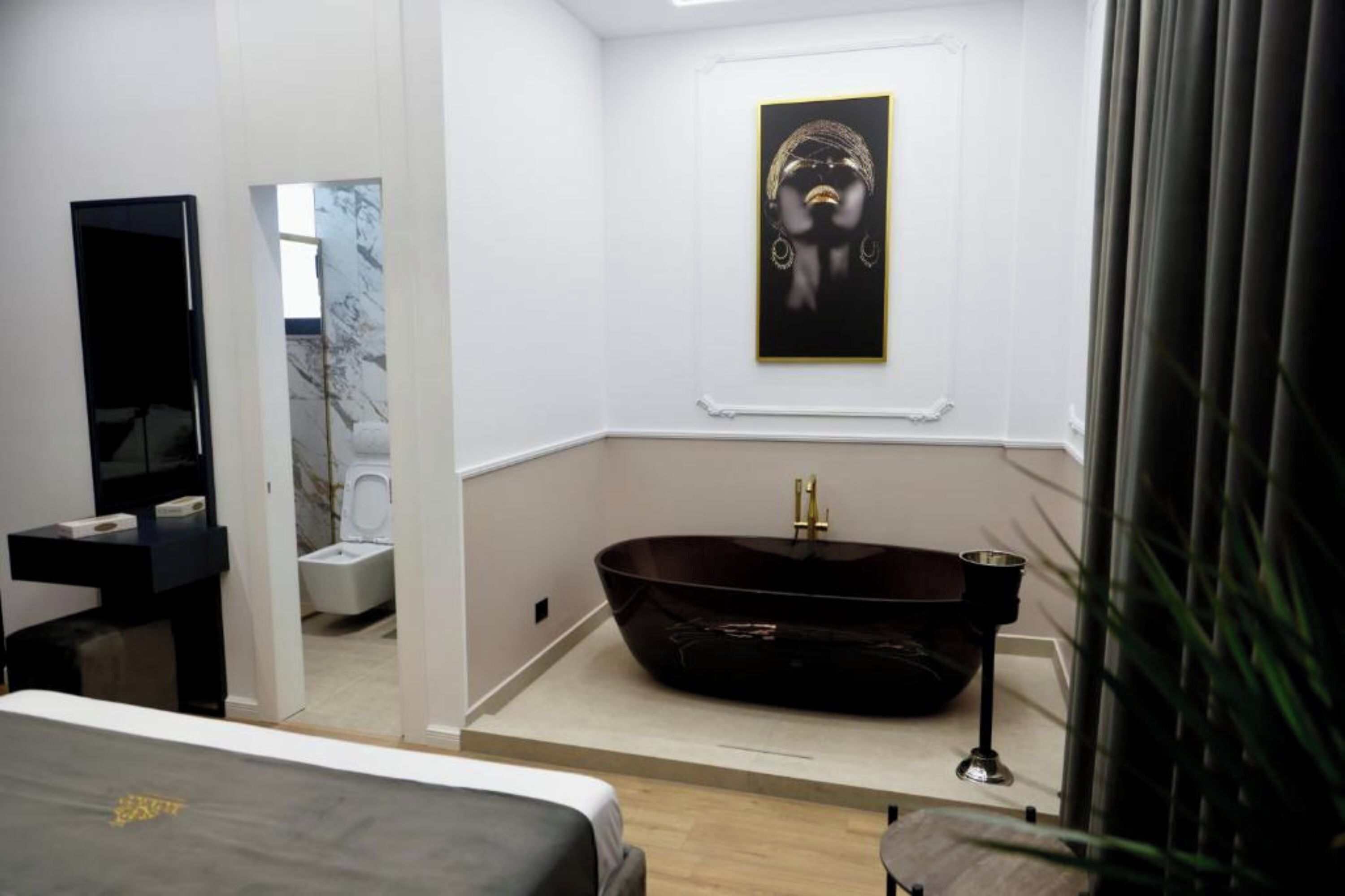 A modern bathroom with a freestanding bathtub, a mirror, and a framed artwork on the wall.
